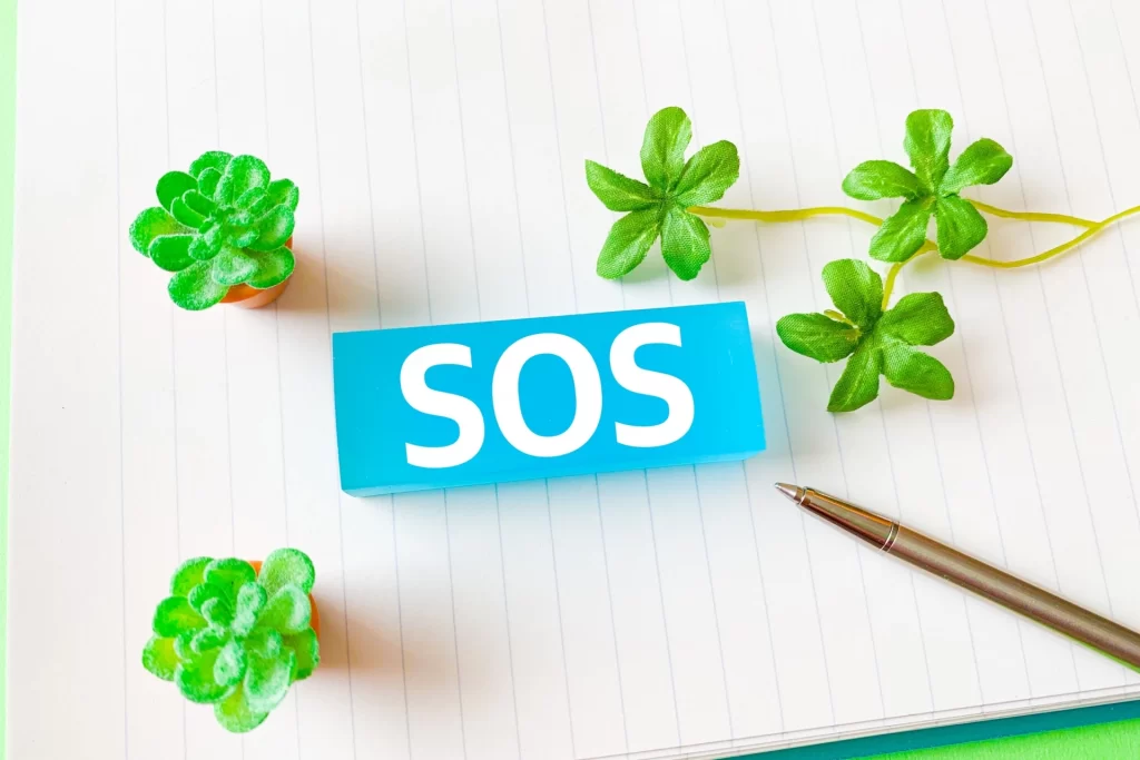 信頼できる外部相談先や公的な支援リソースを求める際の見印となる、SOSと書かれた青いブロックのイメージ画像